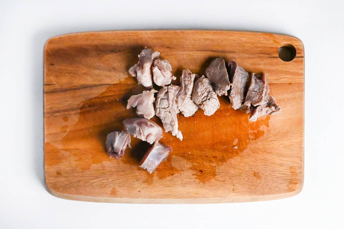 beef sinew cut into bitesize pieces on a wooden chopping board