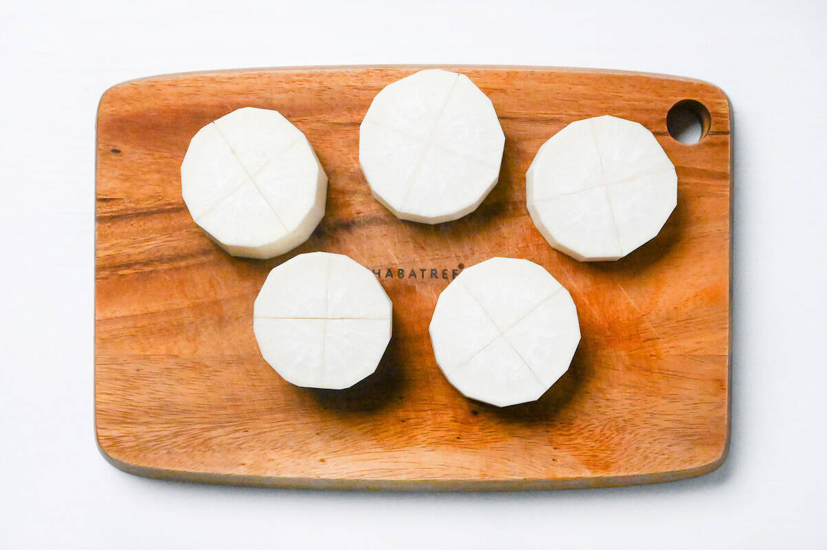 daikon radish peeled and cut into rounds, scored with a cross on a wooden chopping board