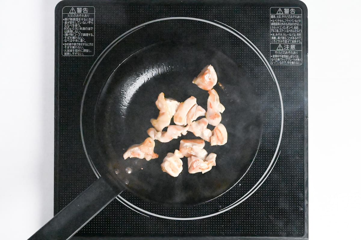 frying chicken thigh in a pan to make ozoni