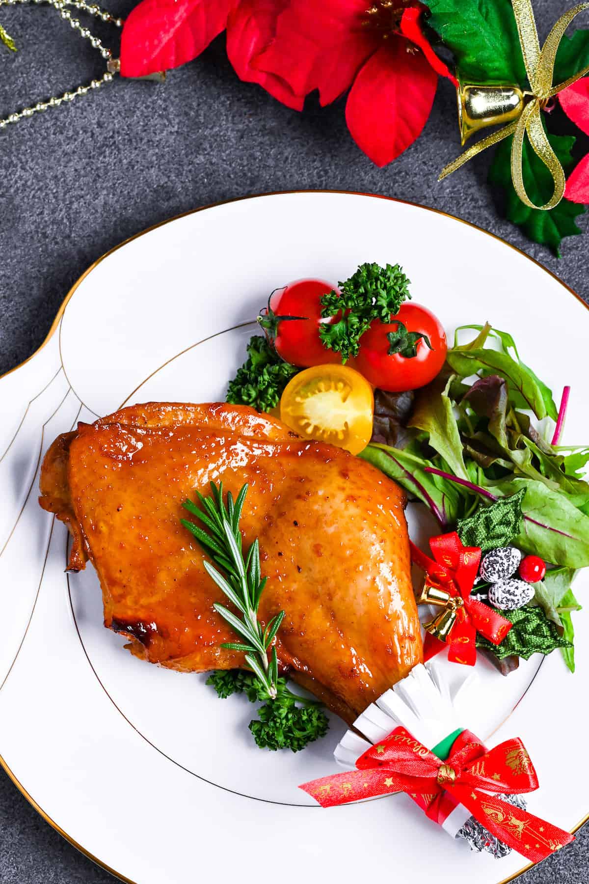 Japanese Christmas Chicken (Roasted Chicken with Soy and Yuzu Glaze) on a white plate topped with a sprig of fresh rosemary next to a simple side salad top down