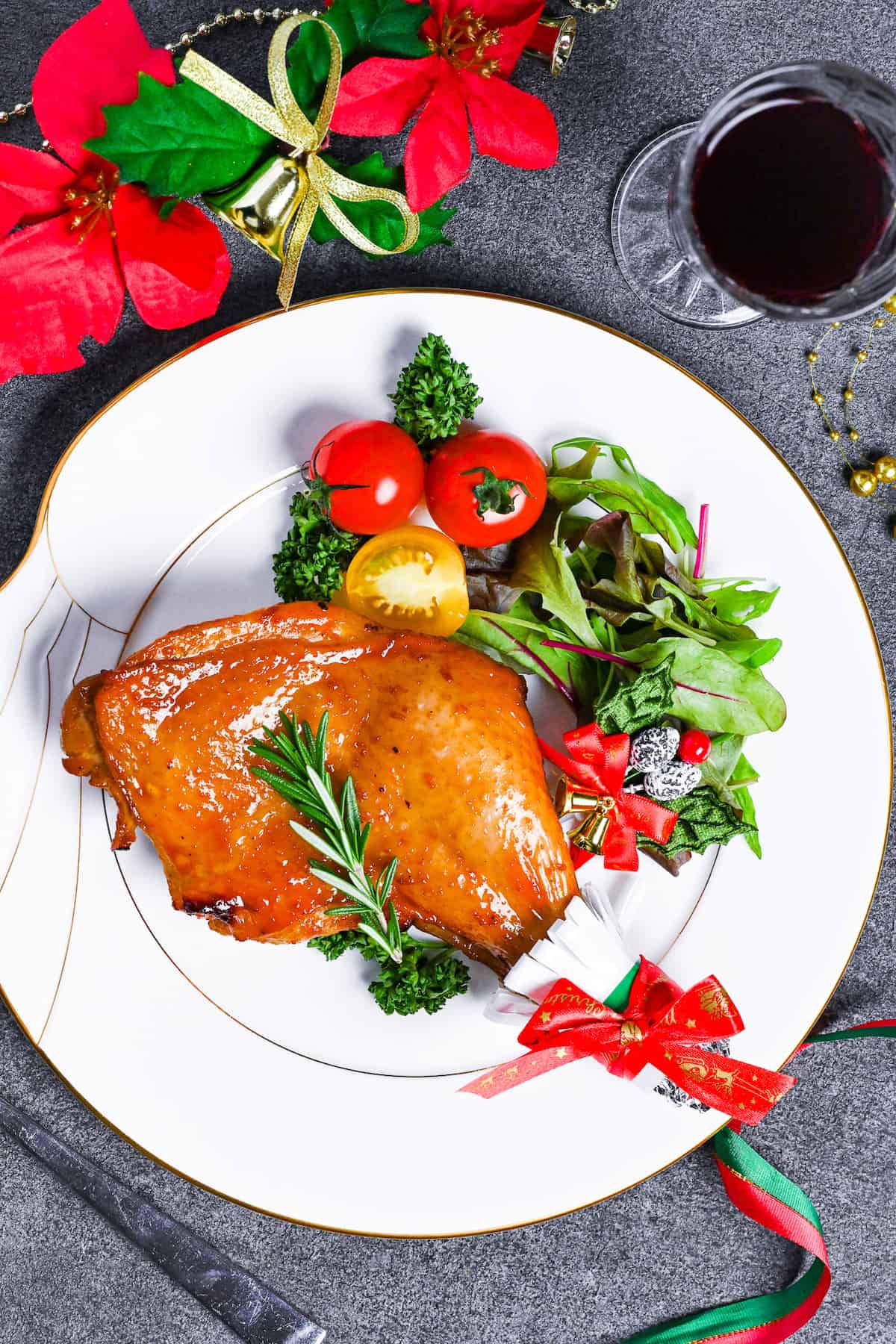 Japanese Christmas Chicken (Roasted Chicken with Soy and Yuzu Glaze) on a white plate topped with a sprig of fresh rosemary next to a simple side salad