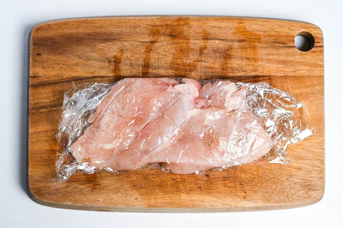 chicken breast wrapped with plastic wrap and tenderized