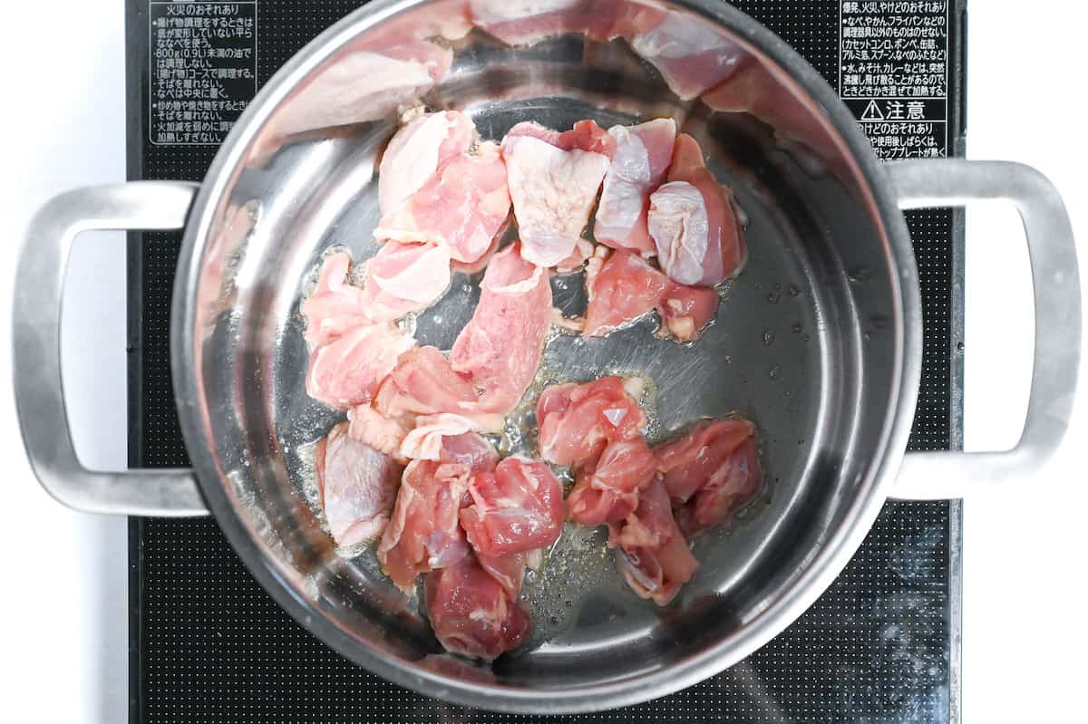 sealing chicken thigh in oil in a large pot on the stove top