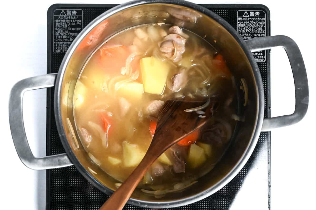 chicken and vegetables in cooking liquid in a large pot on the stove top