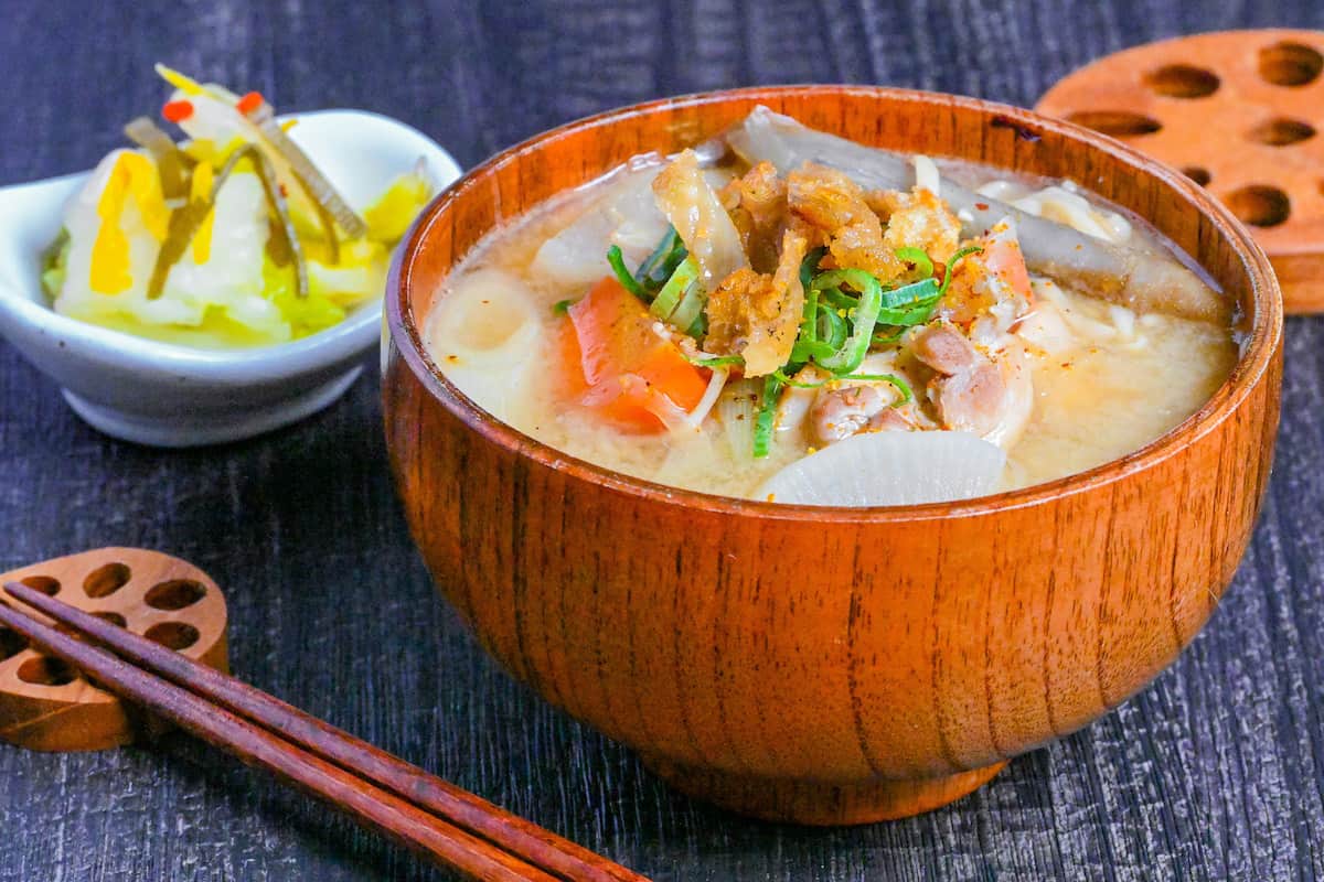 Japanese Chicken Miso Soup (Torijiru) in a wooden bowl topped with green onion and strips of crispy chicken skin