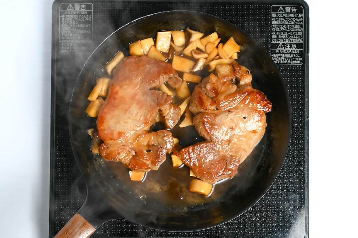 pork chops frying in a pan with teriyaki sauce and eryngii mushrooms
