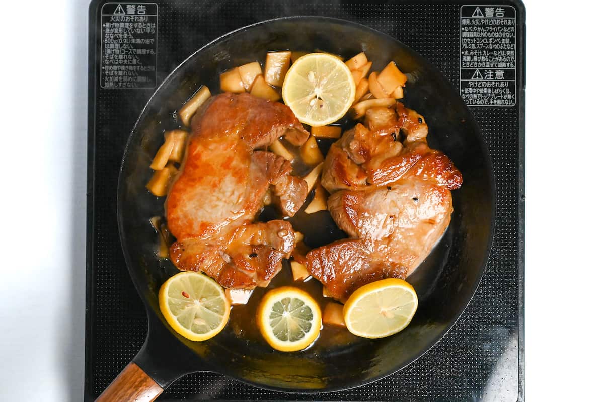 pork chops in a pan with teriyaki sauce, eryngii mushrooms and lemon slices