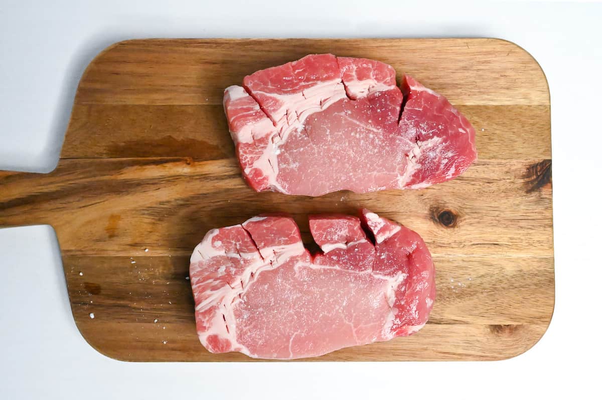 seasoned pork chops on a wooden chopping board