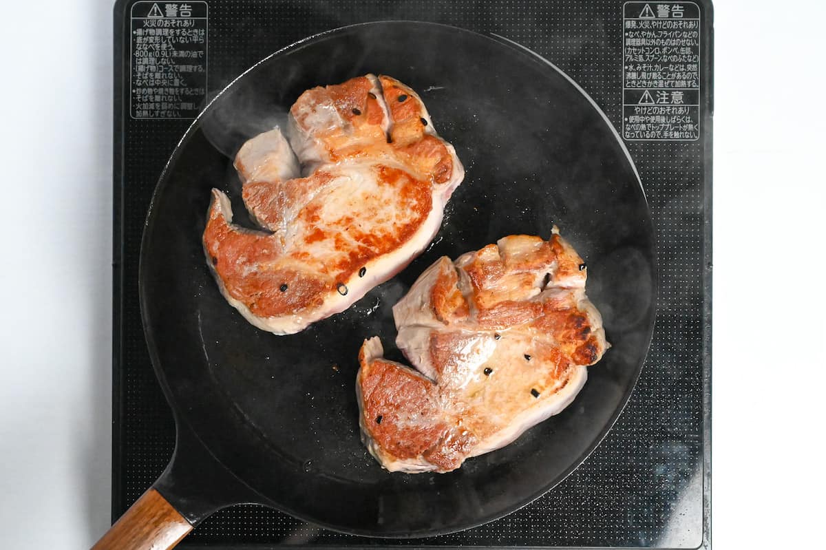 frying pork chops in a pan until golden on the surface
