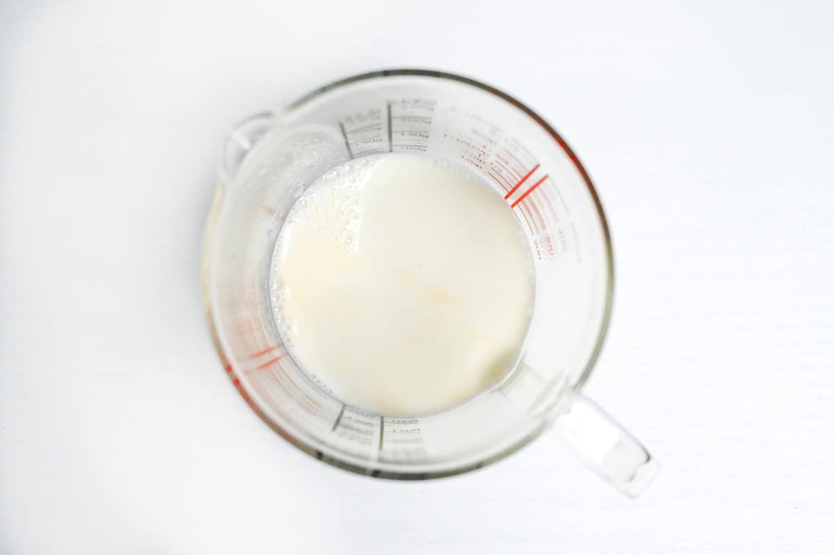 whole milk and a drop of vanilla essence in a glass measuring jug