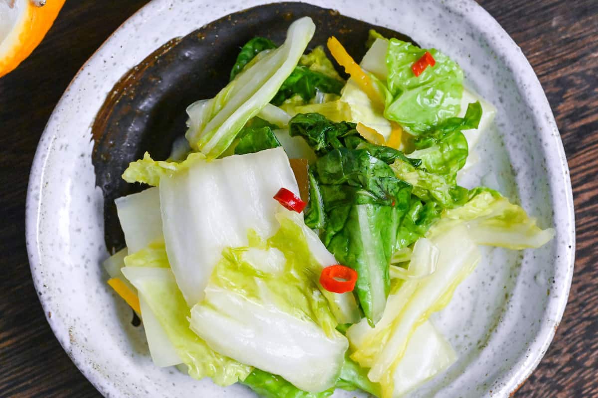 Japanese Napa Cabbage Pickles (Hakusai No Asazuke) on a small white plate with brown brushstroke design closeup