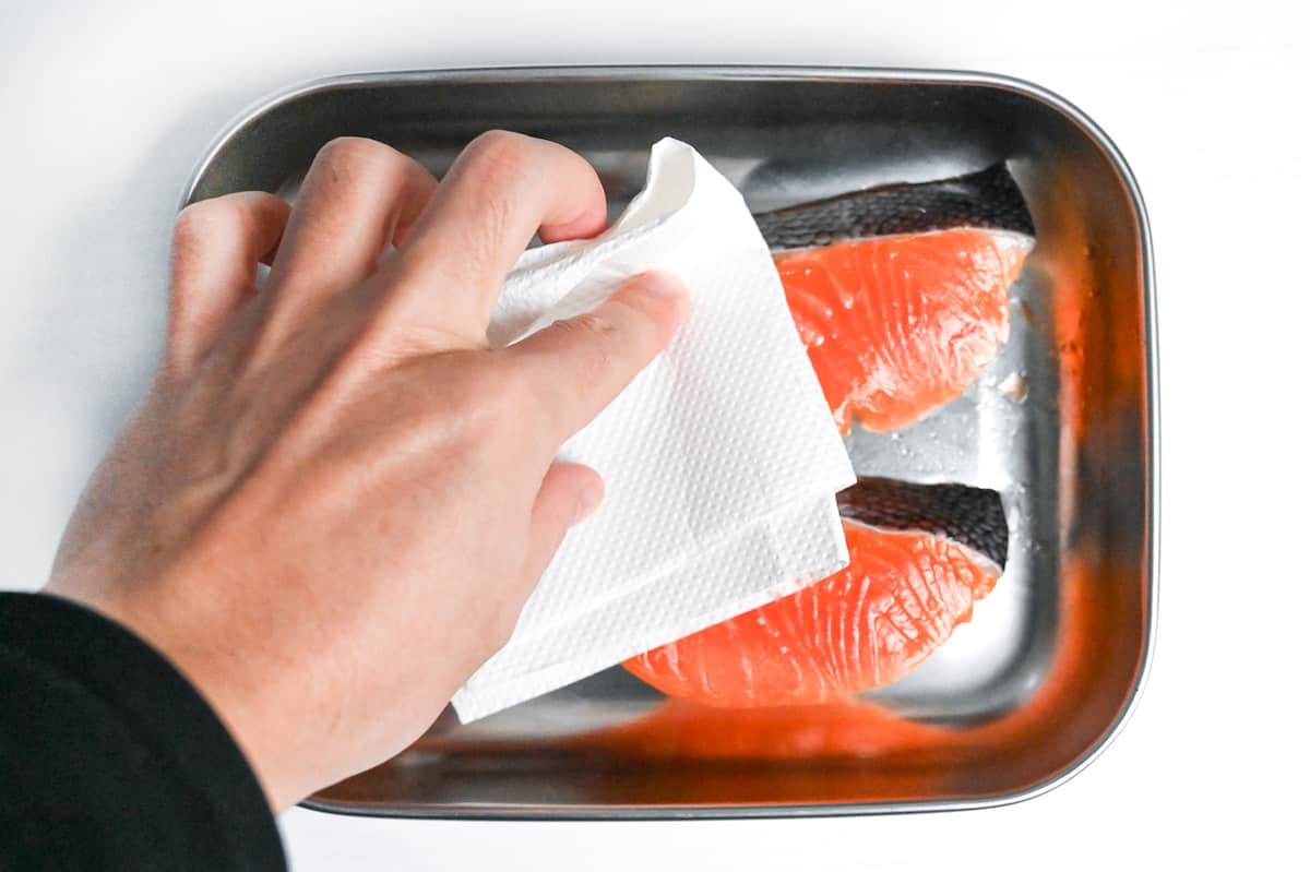 patting salmon fillets dry with kitchen paper