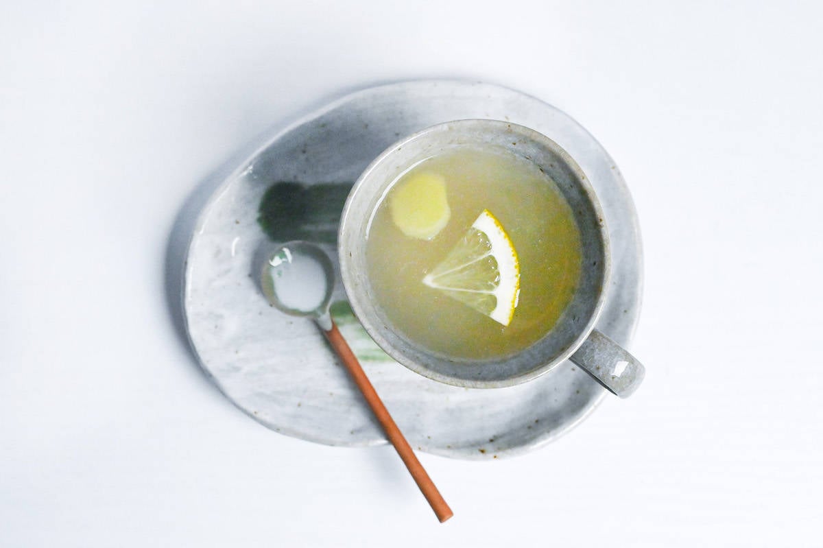 shogayu in a gray cup with a slice of ginger and a lemon wedge