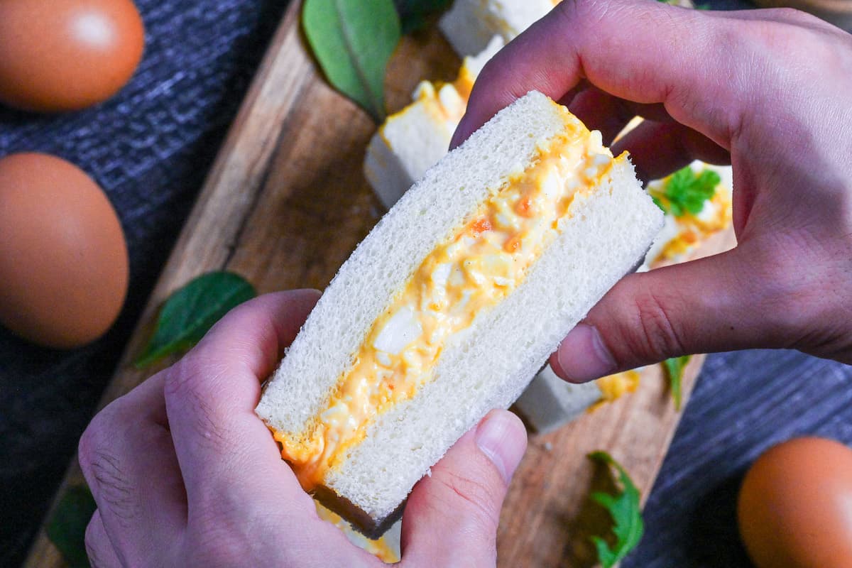 holding Japanese egg sandwich (tamago sando) in two hands