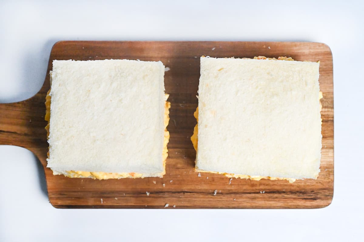 two complete tamago sando (Japanese egg mayo sandwiches) on a wooden chopping board