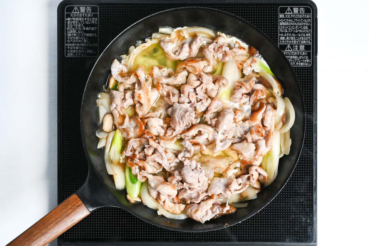 Pork and vegetables coated with egg whites in a frying pan