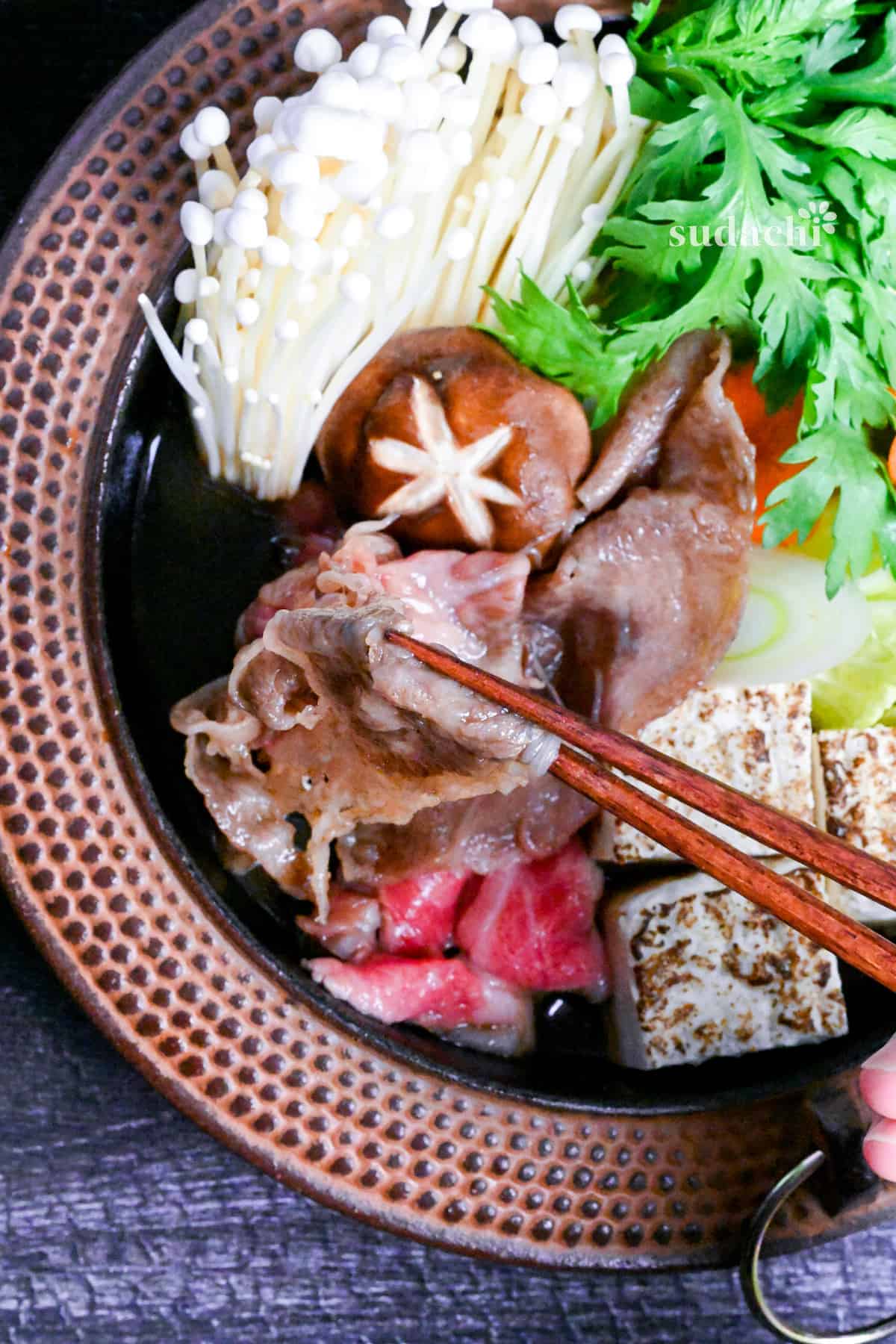 Traditional Japanese beef sukiyaki made with homemade sauce, thinly sliced wagyu beef, grilled tofu, shiitake mushrooms, enoki, carrots, napa cabbage, Japanese leeks and napa cabbage in a cast iron pot