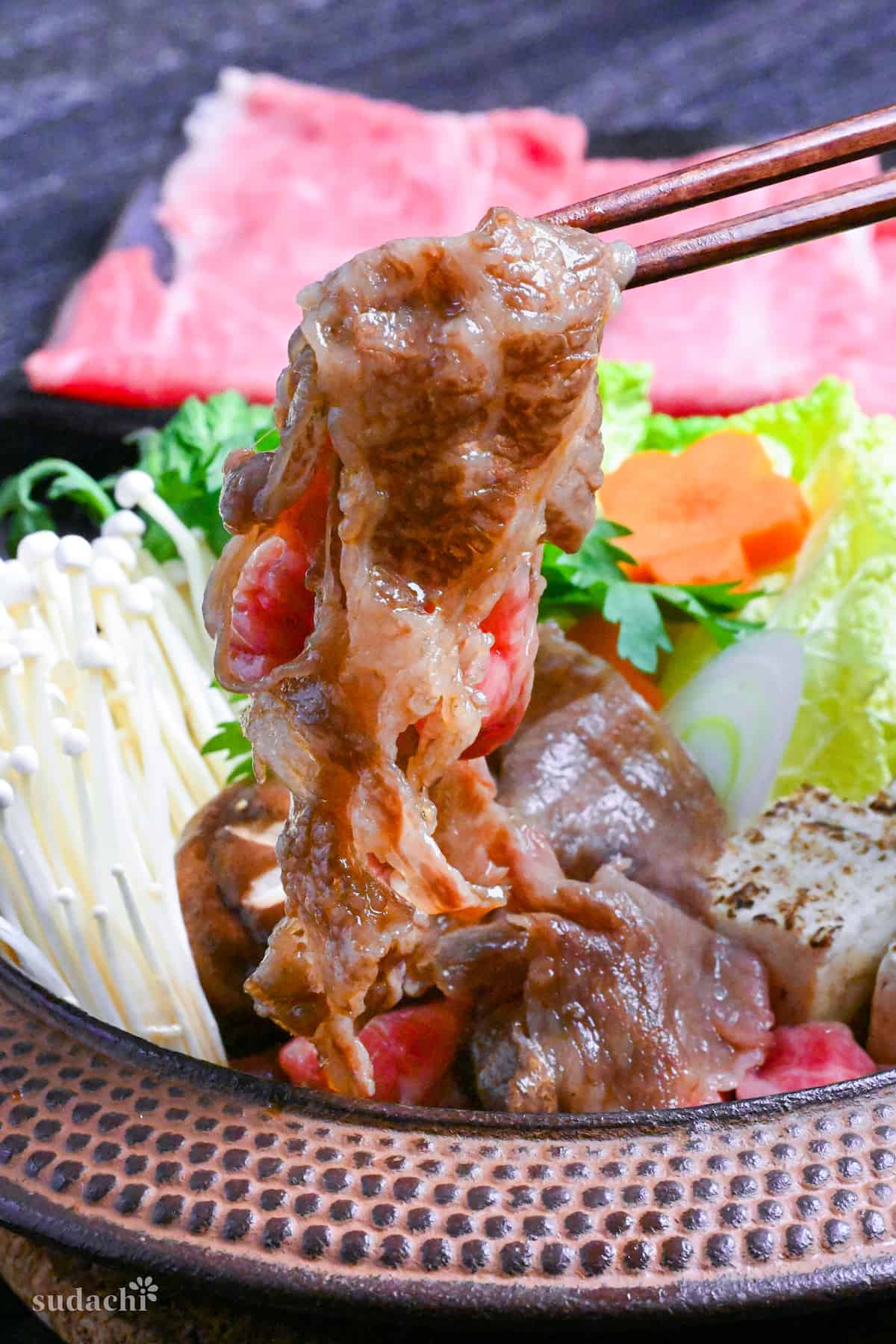 Traditional Japanese beef sukiyaki made with homemade sauce, thinly sliced wagyu beef, grilled tofu, shiitake mushrooms, enoki, carrots, napa cabbage, Japanese leeks and napa cabbage in a cast iron pot