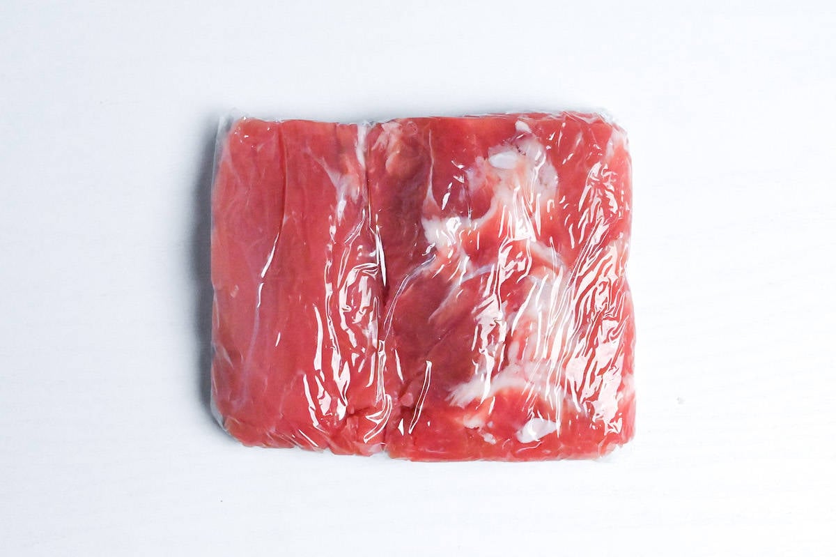 tenderized pork fillet shaped into a rectangle and wrapped with plastic wrap