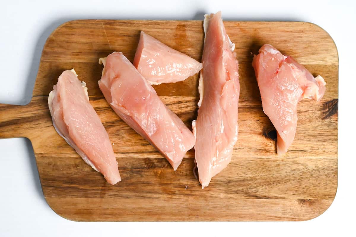 chicken breast cut into pieces on a wooden chopping board