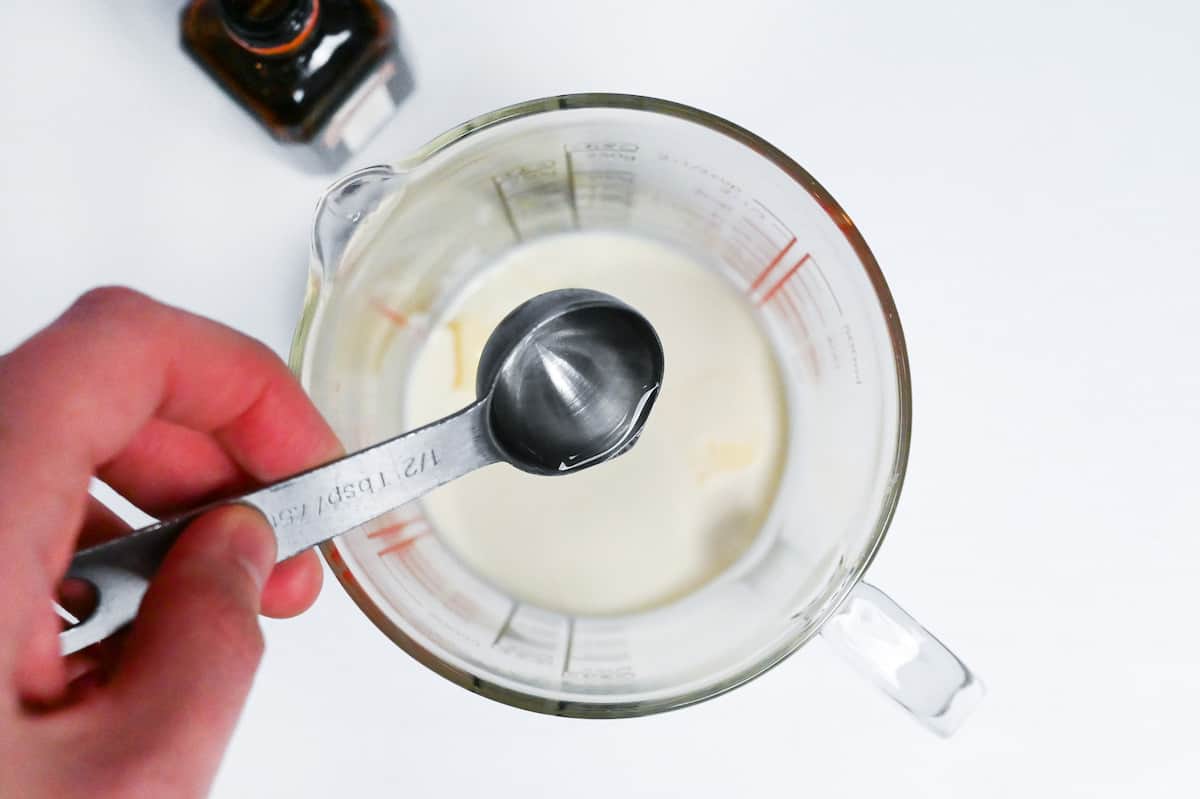 pouring liquor into cream and butter mixture in a glass measuring jug