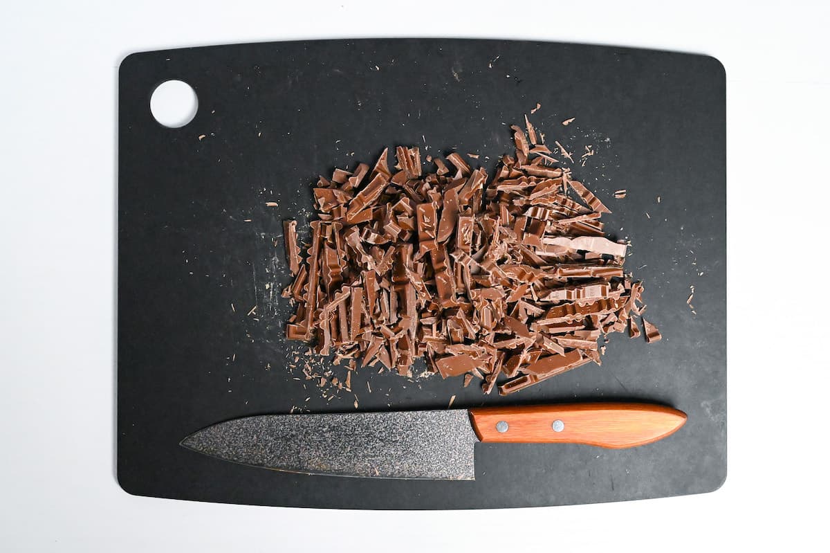 milk chocolate cut into fine pieces on a black chopping board