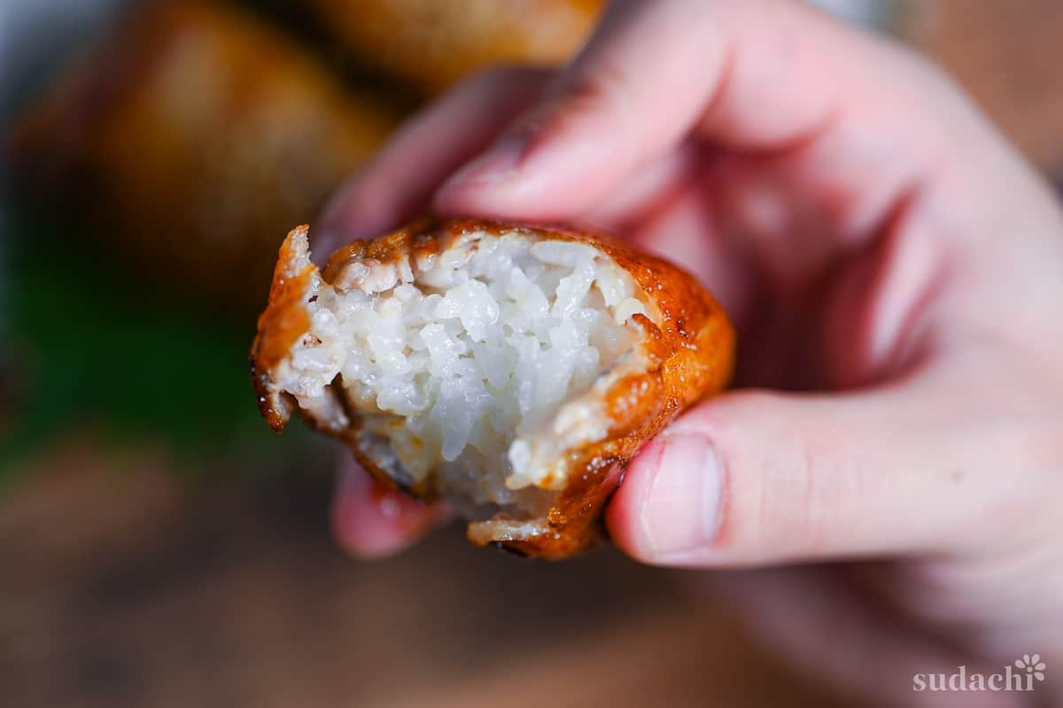 Nikumaki Onigiri (Pork belly wrapped rice ball) held in hand with bite missing