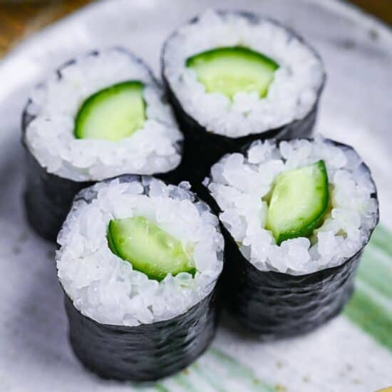 4 kappa maki (cucumber sushi rolls) on a gray plate with green brush effect close up