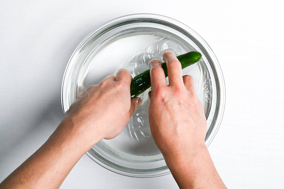 washing cucumber in a bowl of fresh water