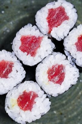 six tekkamaki tuna sushi rolls on a green plate top down close up