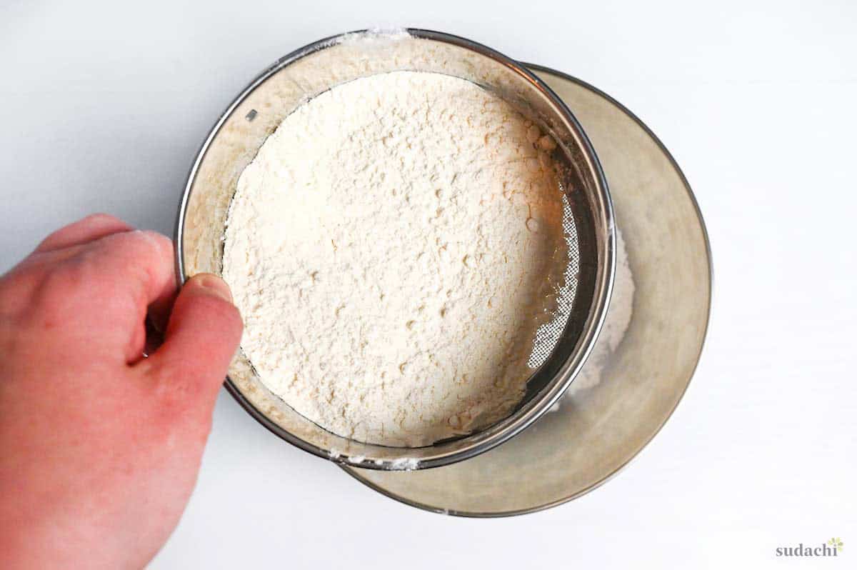 sifting flour into a steel mixing bowl