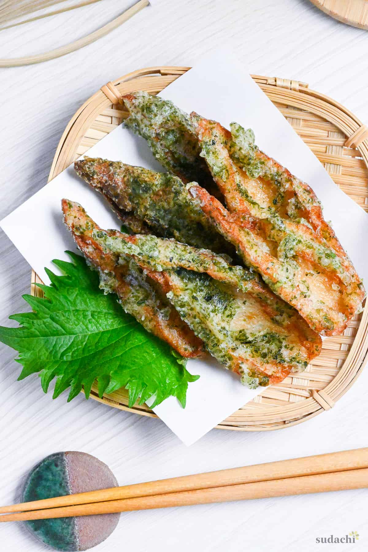 Chikuwa isobeage on a bamboo tray with tempura paper and a shiso leaf