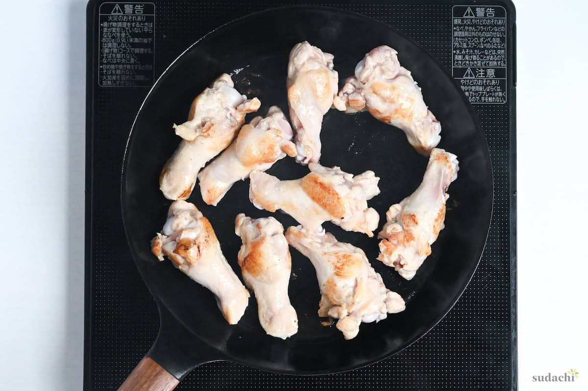 seared chicken drumsticks in a black frying pan