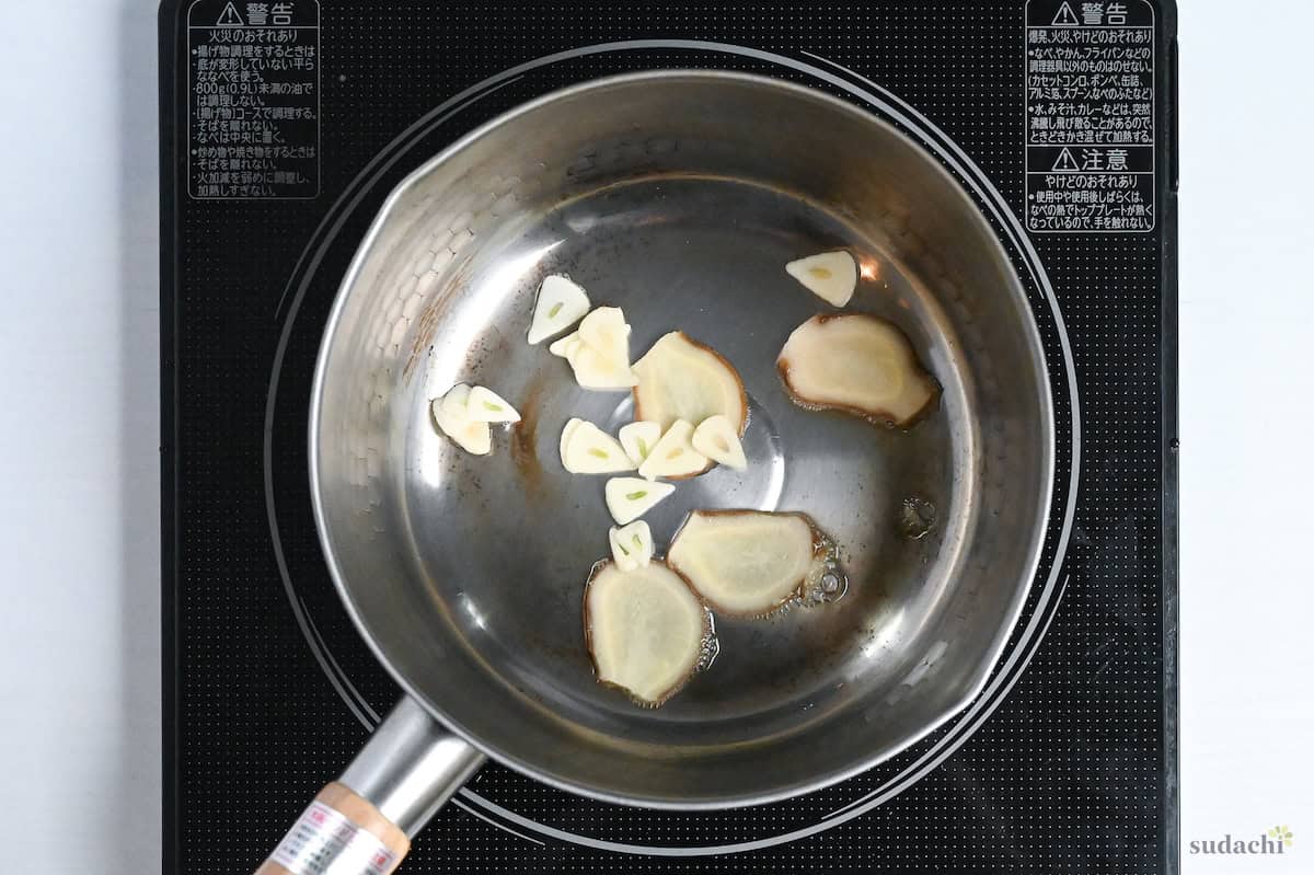 slices of garlic and ginger frying in a pot