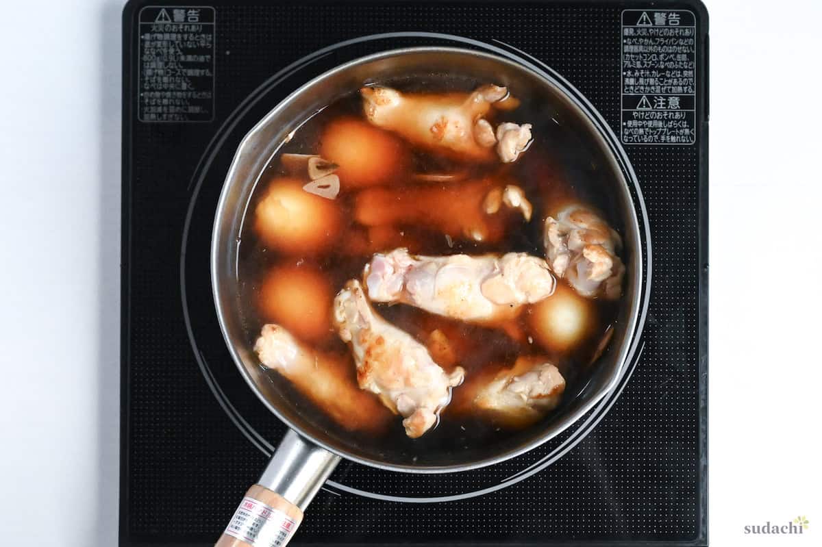 chicken and eggs in vinegar based broth simmering in a pot on the stove