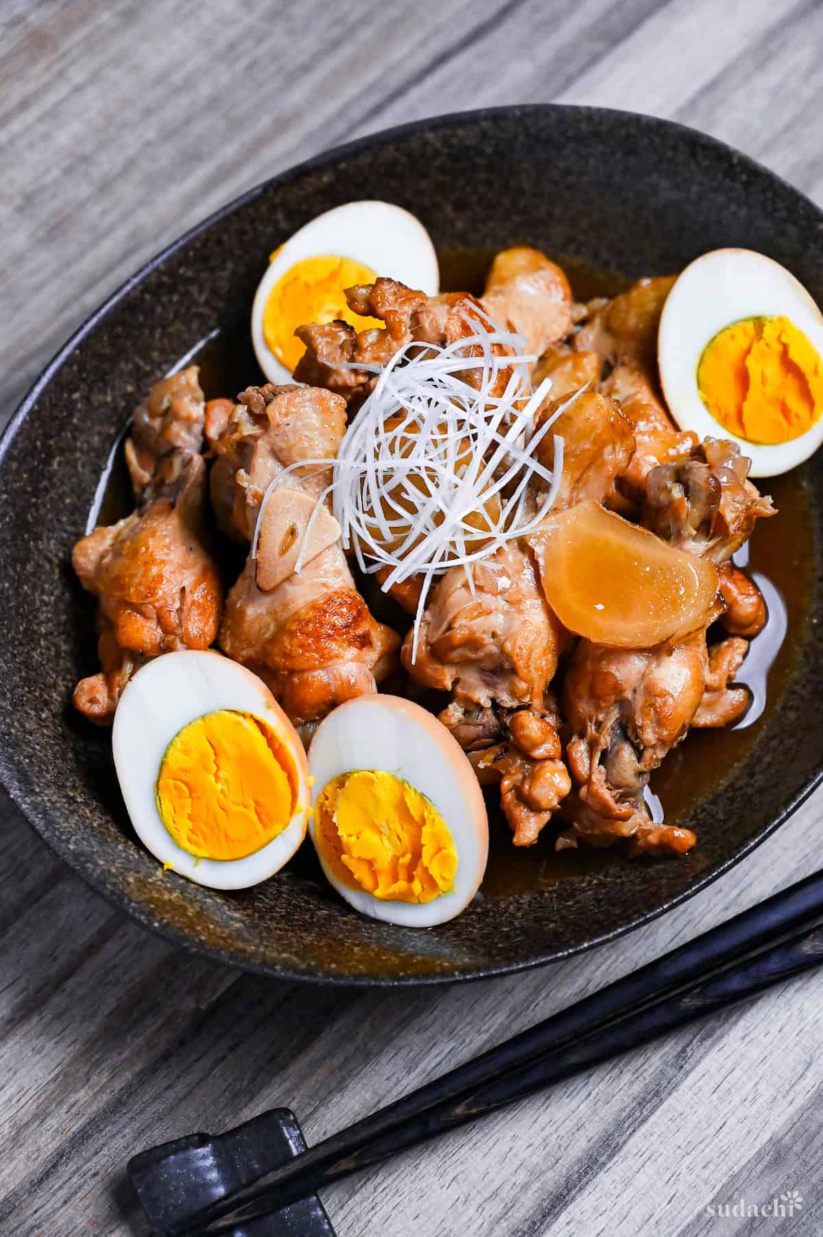 Tori no Sappari-ni made with chicken drumsticks and boiled eggs simmered in a vinegar based broth served in a black oval shaped bowl