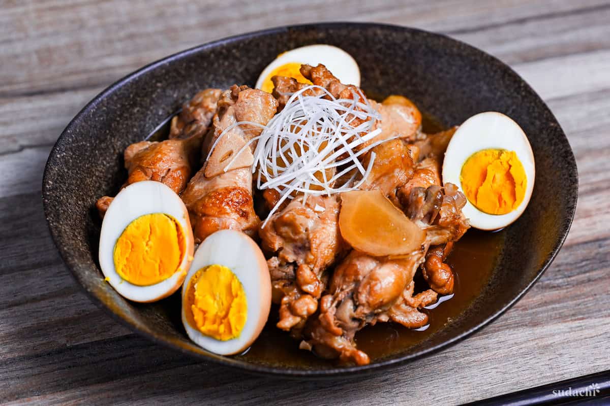 Tori no Sappari-ni made with chicken drumsticks and boiled eggs simmered in a vinegar based broth served in a black oval shaped bowl