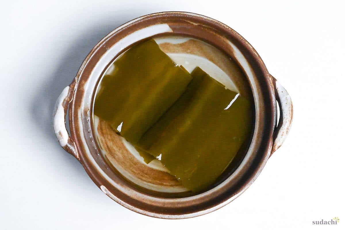 kombu soaking in a brown pot of water with handles