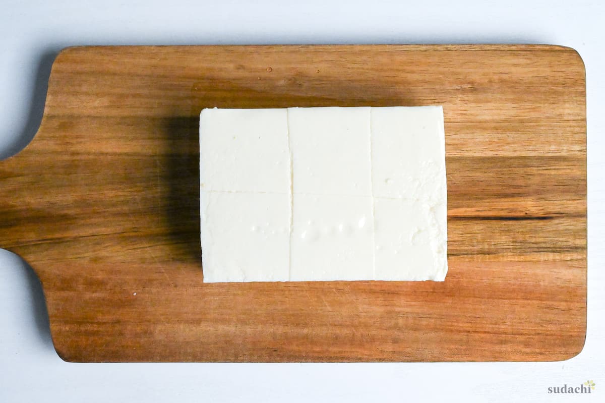 firm tofu cut into large cubes on a wooden chopping board