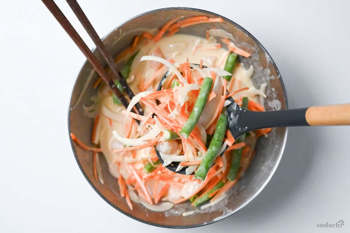 Using a ladle to scoop up kakiage batter and ingredients