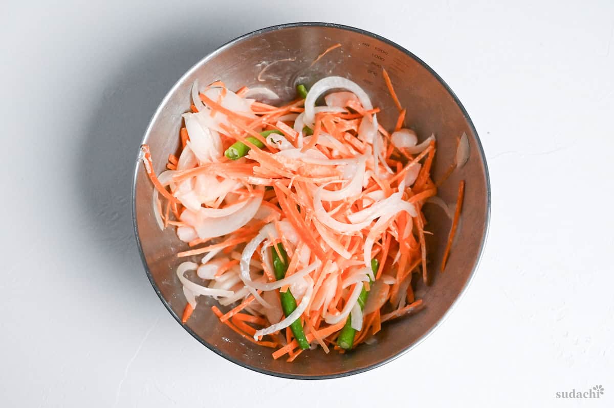 thinly sliced carrot, runner beans, onion and shrimp in a mixing bowl