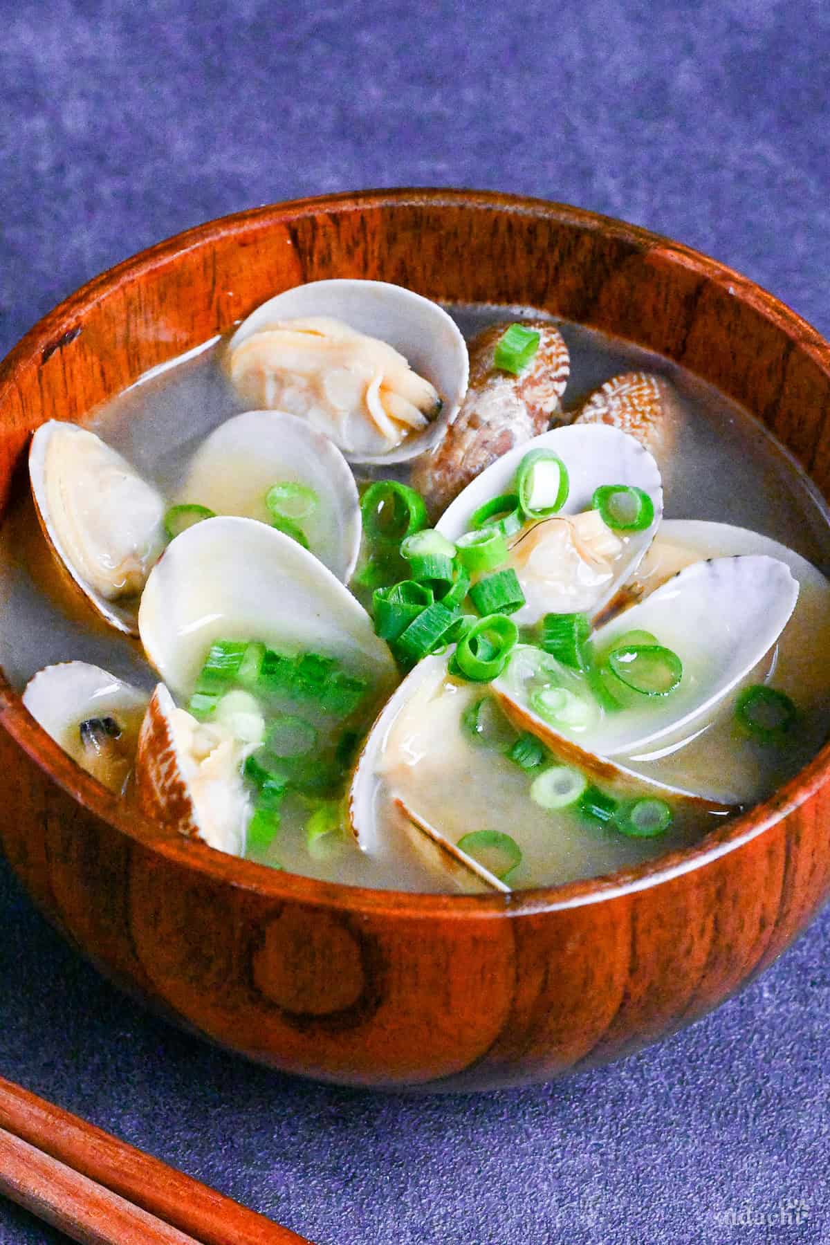 Asari clam miso soup in a wooden bowl on a dark gray background