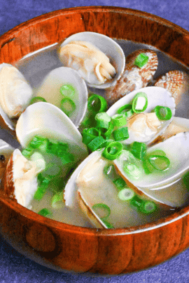 Asari clam miso soup in a wooden bowl on a dark gray background