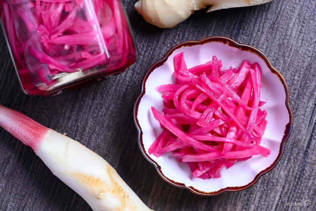 Homemade Japanese red pickled ginger (benishoga) in a white fluted bowl with brown edges