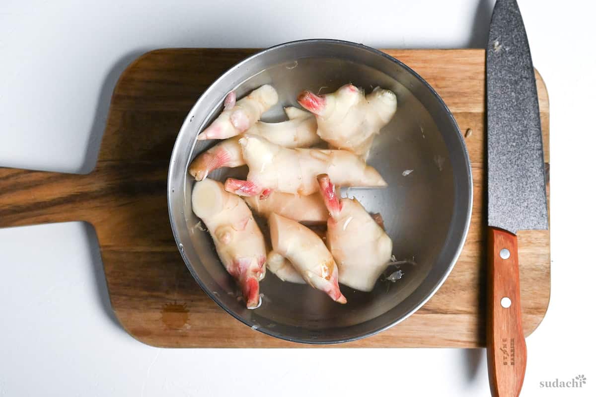 washed young ginger in a bowl of water cut into manageable pieces