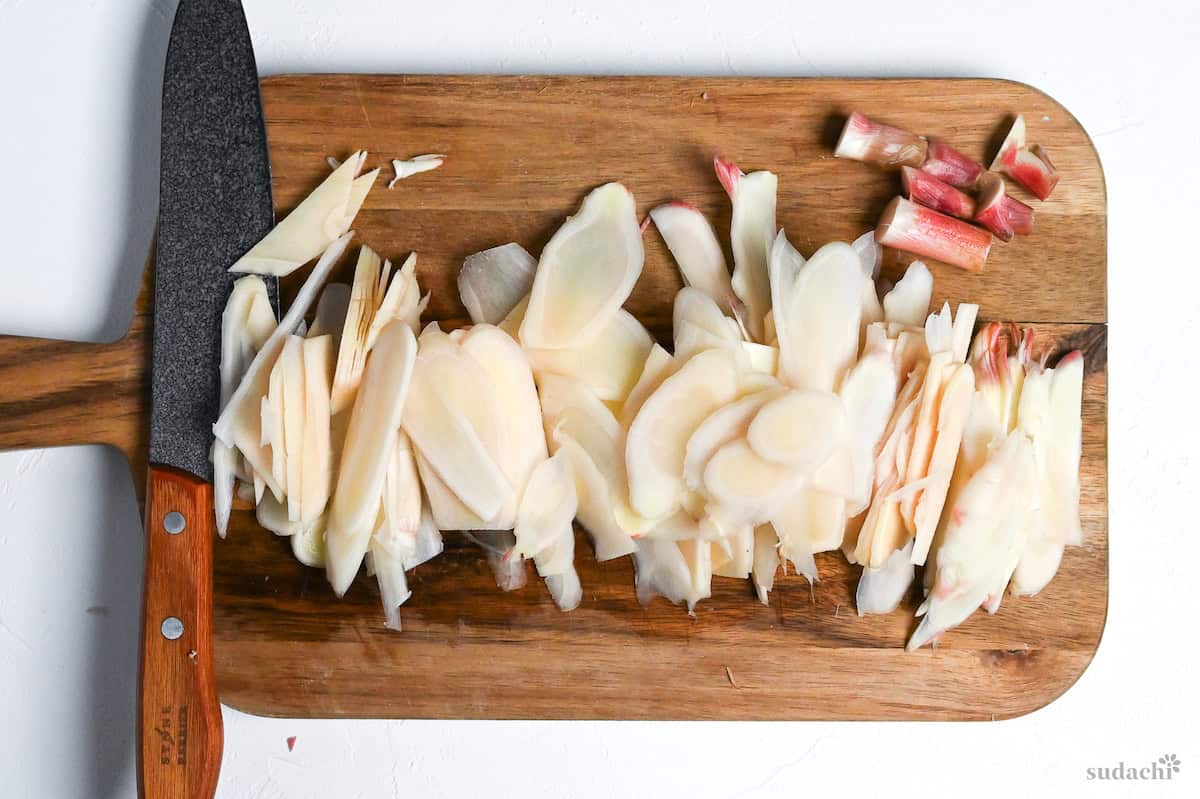 thinly sliced young ginger on a wooden chopping board