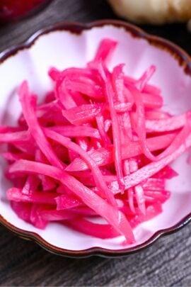 Homemade Japanese red pickled ginger (benishoga) in a white fluted bowl with brown edges