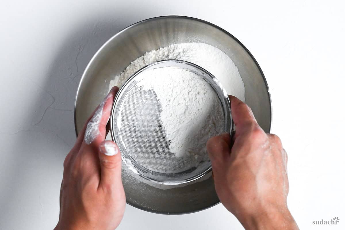 sifting flour into a bowl to make ramen noodle dough