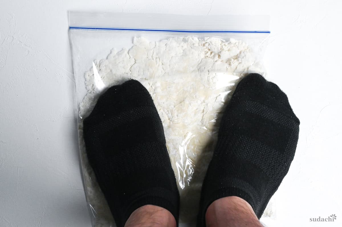 stepping on ramen noodle dough in a sealed plastic bag to knead with feet