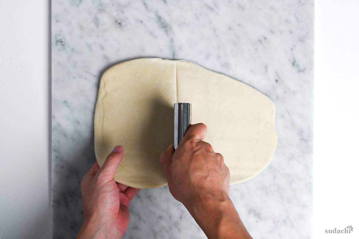 cutting ramen noodle dough into quarters on a marble kneading board